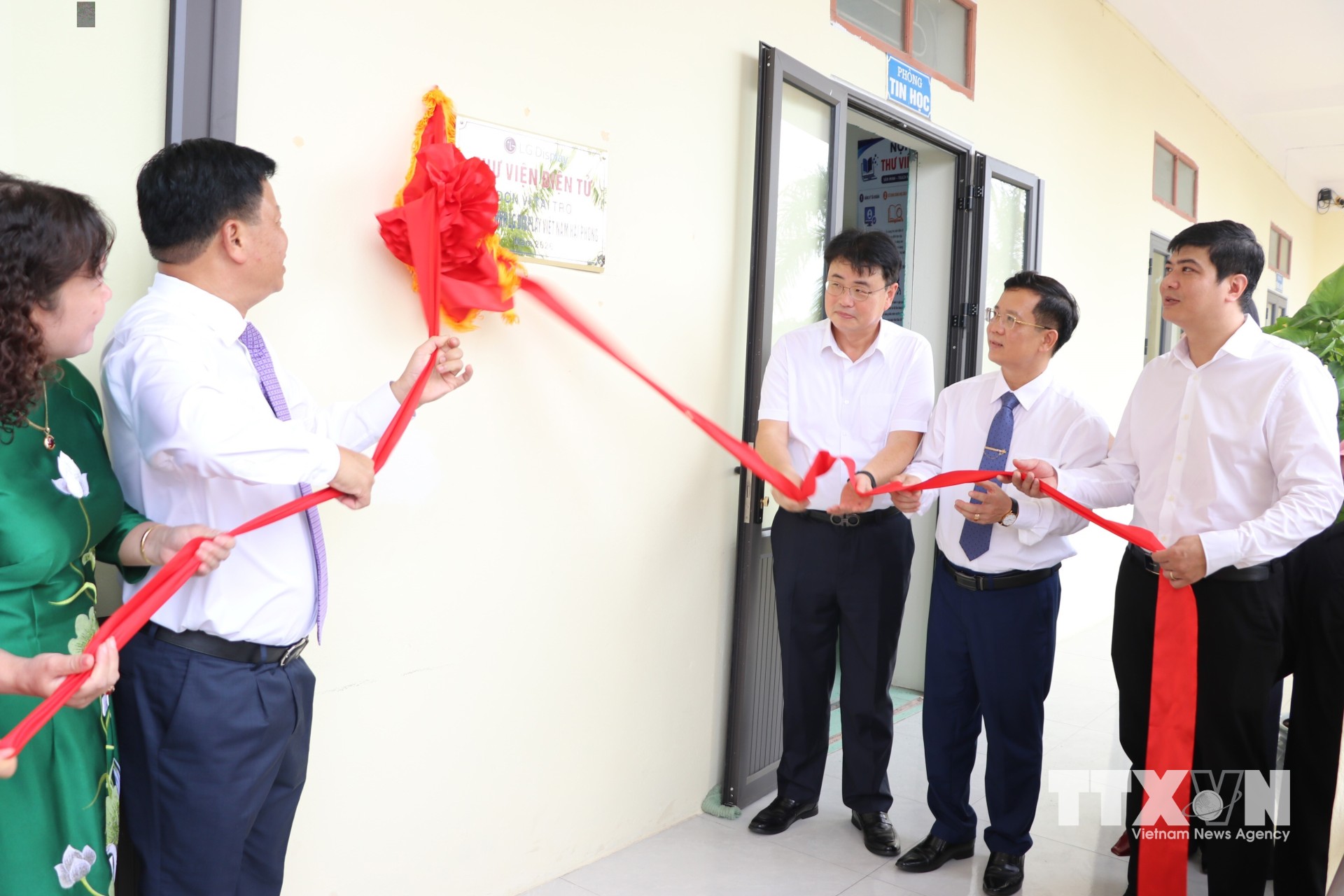 Các đại biểu thực hiện nghi thức kéo băng khánh thành Thư viện điện tử Trường THCS An Thành. (Ảnh: Mạnh Tú/TTXVN)